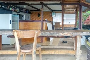 A rustic kitchen with a wooden table and chairs, a refrigerator, and a wooden counter. - Rejeng Bungalow near Gangga Waterfall Lombok (Genggelang)