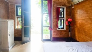Una habitación con cama, armario y ventana con cortinas.