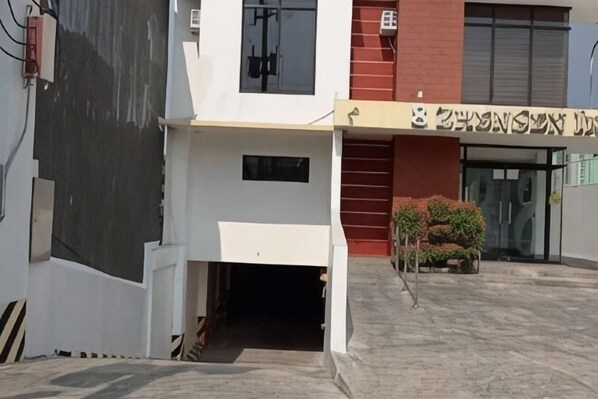Un bâtiment à la façade blanche, une porte rouge et une enseigne avec des caractères qui ne sont pas de l’alphabet anglais.