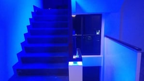 Eine Treppe mit blauer Färbung, einer Glastür und einem weißen Geländer.