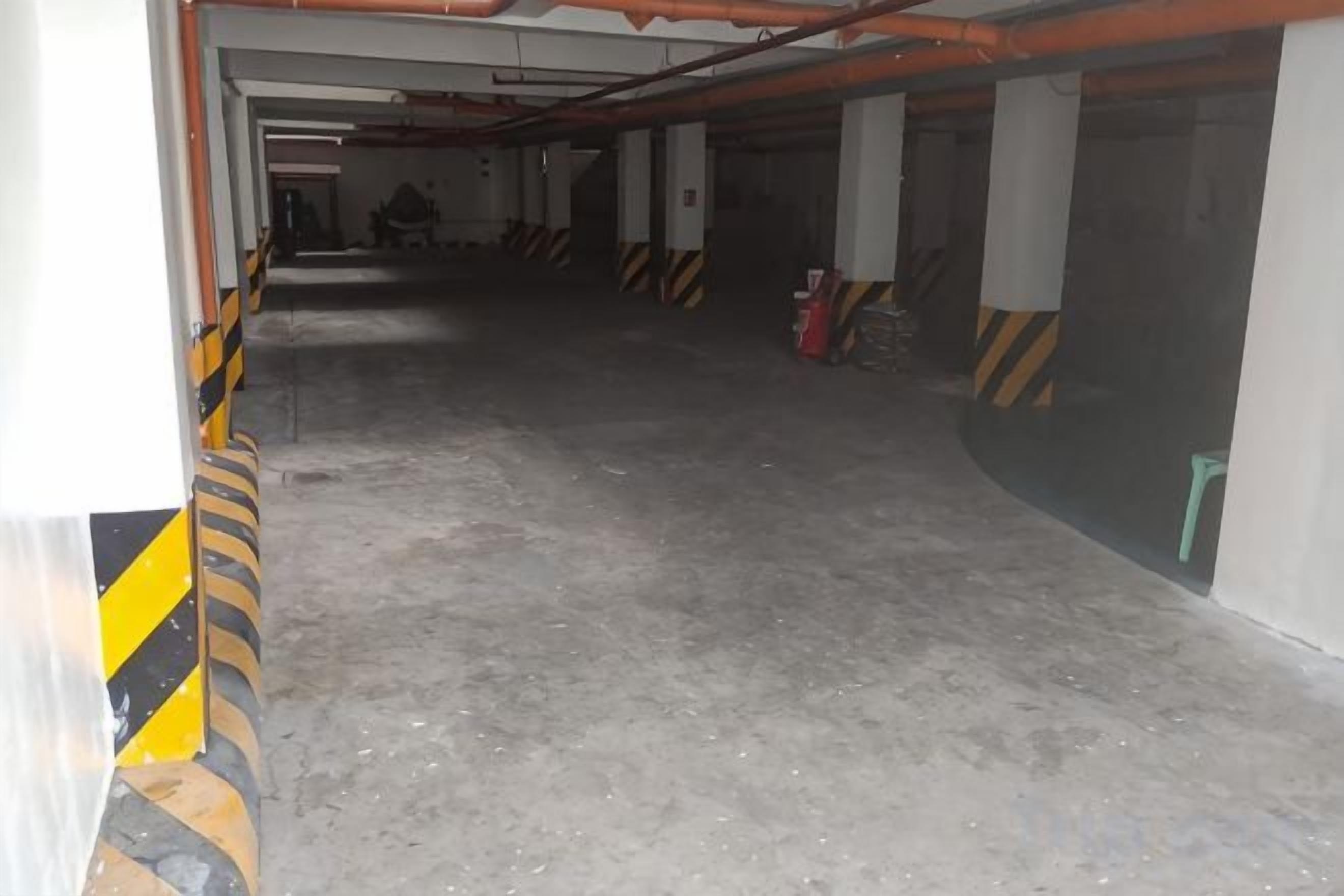 Garagem de estacionamento com pisos de concreto e barreiras de segurança listradas.
