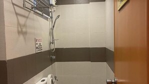 Ein kleines, abgeschlossenes Badezimmer mit Toilette, Dusche und einem Handtrockner.