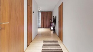 A hallway with wooden doors, a patterned rug, and a ceiling light fixture. - Premium Downtown Queen Apartment KARTULI (Reykjavík)