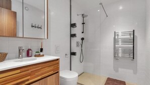 A modern bathroom with a glass shower enclosure, a white toilet, and a wooden vanity with a sink. - Premium Downtown Queen Apartment KARTULI (Reykjavík)
