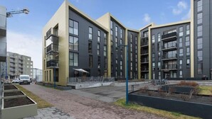 A modern apartment building with multiple balconies, a paved walkway, and a small garden area. - Premium Downtown Queen Apartment KARTULI (Reykjavík)