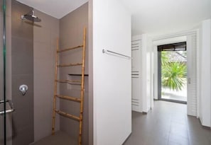 Un baño con ducha, una escalera de bambú y un perchero para toallas.
