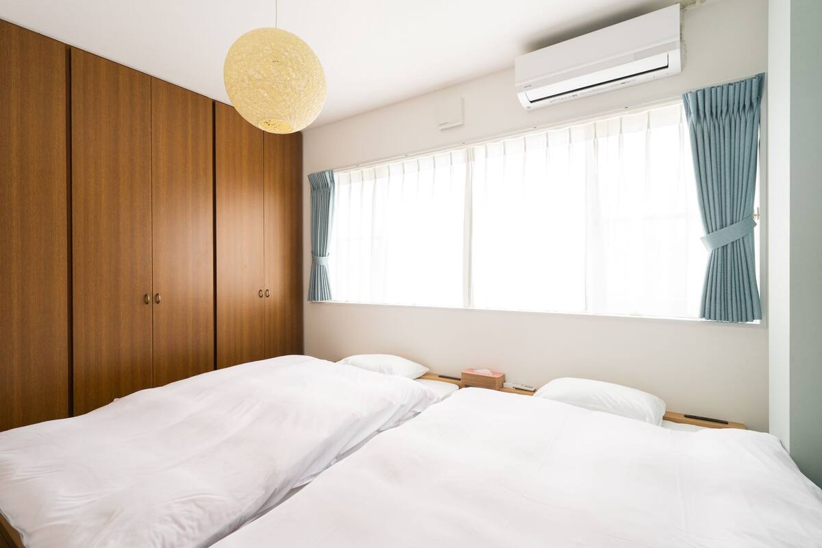 Een slaapkamer met een bed, een houten garderobe en een raam met gordijnen.