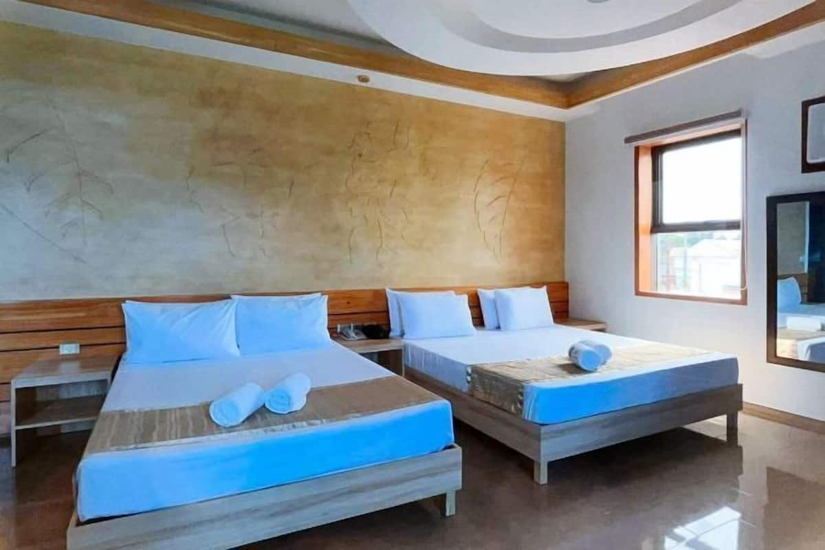 A hotel room with two beds, wooden headboards, and a large window providing natural light.