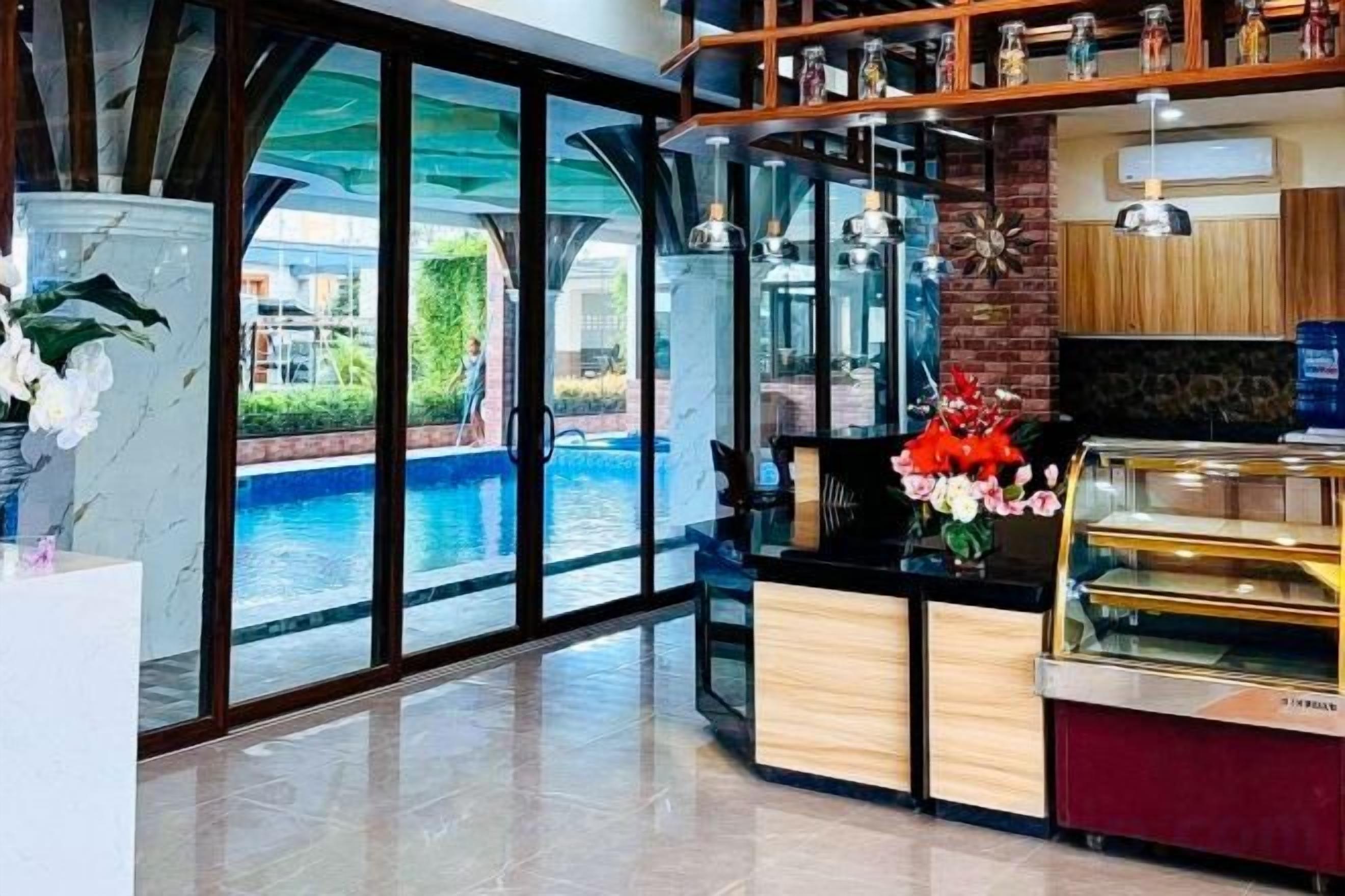 A hotel lobby with a pool view, a reception desk, and a display case.