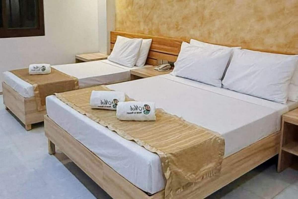A hotel room with two single beds, each with a wooden headboard and white bedding. There are two bedside tables, one with a phone and the other with a tissue box.