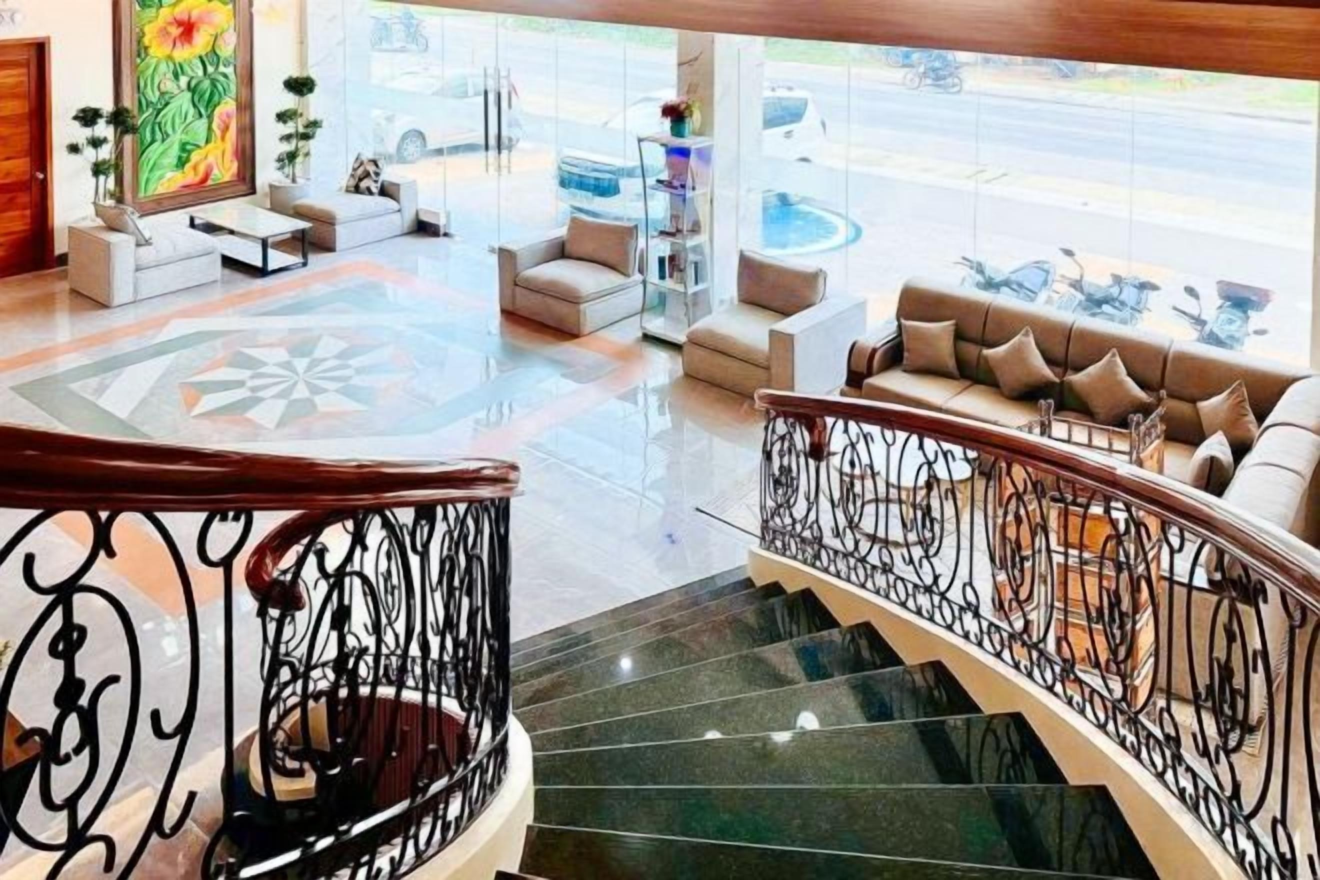 A hotel lobby with a staircase, seating area, and a view of the street.