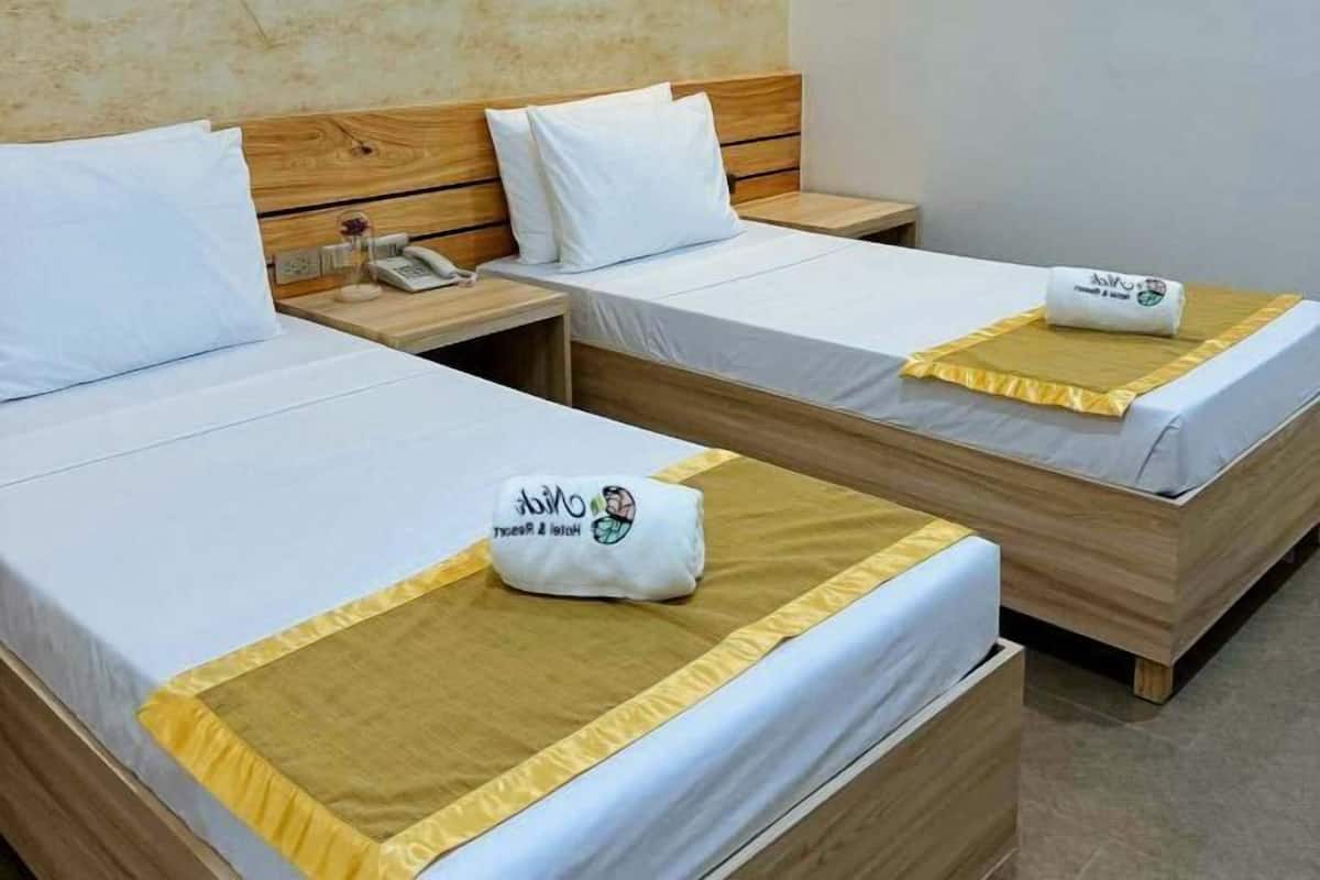 Two single beds with wooden headboards, white bedding, and a small table with a telephone.