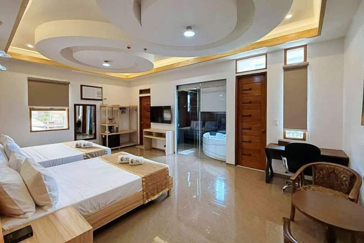 A hotel room with two beds, a desk, a chair, a wardrobe, and a bathroom.