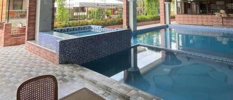An outdoor pool area with a seating area and a hot tub.