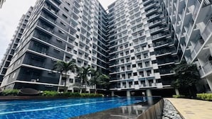 A modern high-rise residential building with a central swimming pool surrounded by greenery. - Solana Staycation Suites at Shore 3 Residence (Pasay)