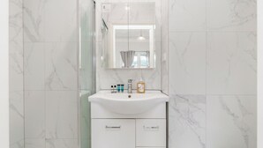 Une salle de bain avec un lavabo en marbre blanc, un miroir et des toilettes.