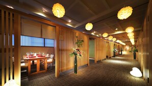 A hotel corridor with wooden paneling, a reception desk, and hanging lamps. - Hanaakarinoyado Tsukinoike (Kaminoyama)