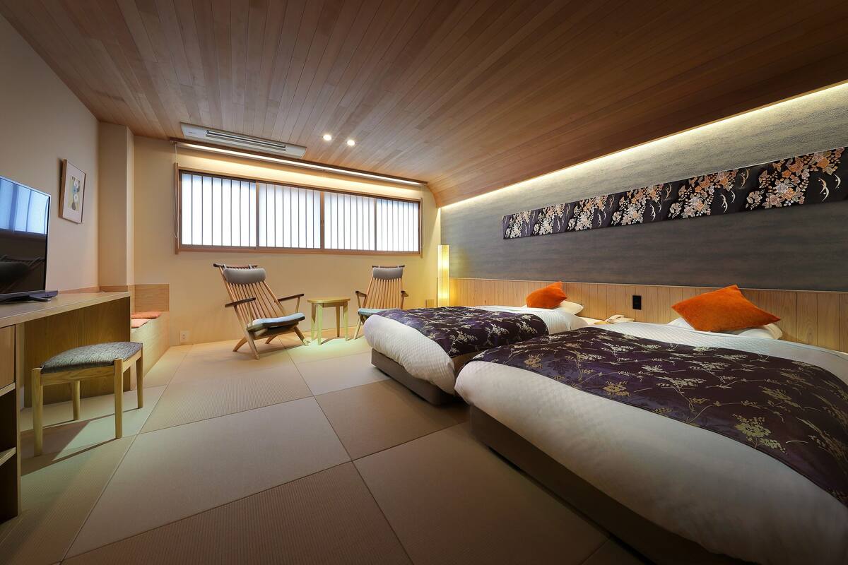A modern hotel room with a large bed, a desk, a chair, and a television.