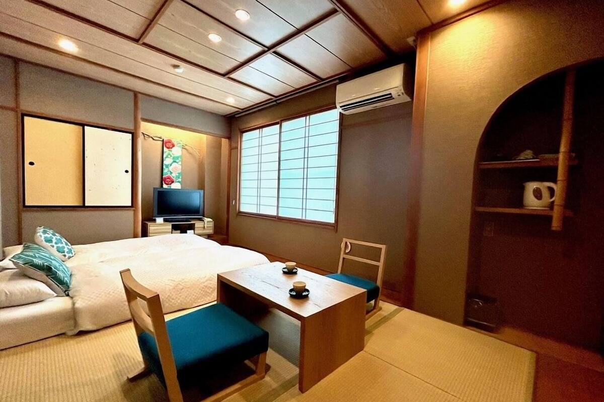 A traditional Japanese-style room with tatami flooring, a bed, a television, and a sliding door.