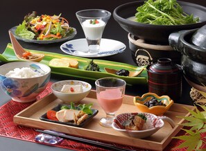 A traditional Japanese meal with various dishes including rice, fish, and vegetables, served on a wooden tray with chopsticks and a glass of drink. - Hanaakarinoyado Tsukinoike (Kaminoyama)