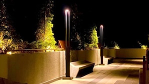 An outdoor terrace with a stone floor, seating areas, and tall, narrow lights. - FZ Homestay @ Putrajaya P5 : Luxury & scenic stay (Putrajaya)