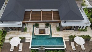 Une maison moderne dotée d’une piscine, d’un espace salon extérieur et d’un patio couvert.