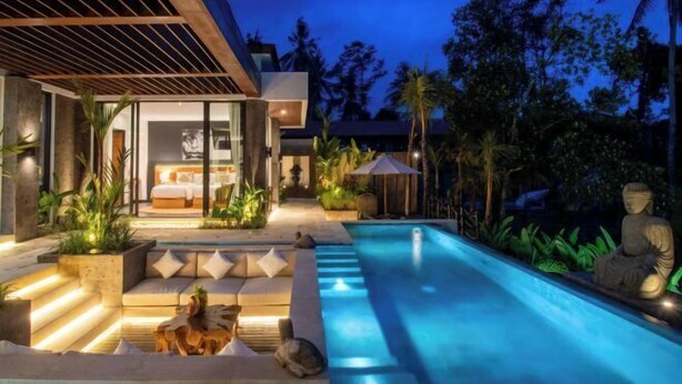 Un espace moderne aménagé autour de la piscine, doté d’un coin salon extérieur bien éclairé, offrant une vue dégagée sur la chambre, et agrémenté d’une statue au bord de la piscine.
