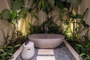 A modern outdoor bathroom with a large stone basin, a small pedestal, and a variety of tropical plants. - Villa Purnama Ubud by BaliSuperHost (Bali)