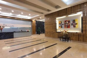A hotel reception area with a reception desk, a wooden wall with framed artwork, and a marble floor. - The Elements @ Ampang (Kuala Lumpur)