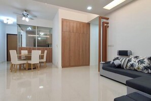 A modern living room with a sofa, a dining table with chairs, and a wooden wardrobe. - The Elements @ Ampang (Kuala Lumpur)