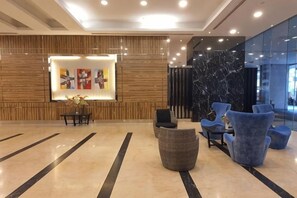 Un vestíbulo moderno con mostrador de recepción, zona de estar y pared de mármol.