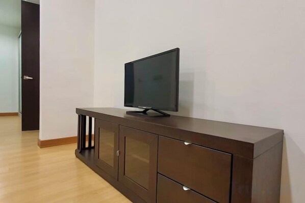 A dark wooden TV stand with a flat-screen TV in a room with white walls and wooden flooring. - The Elements @ Ampang (Kuala Lumpur)
