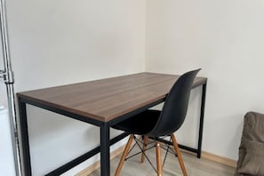 A corner room with a wooden table and a black chair.