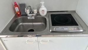 A stainless steel sink with a faucet, soap dispenser, and a bottle of hand soap.