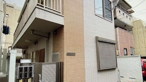 A multi-story residential building with a balcony, a gated entrance, and a small window.