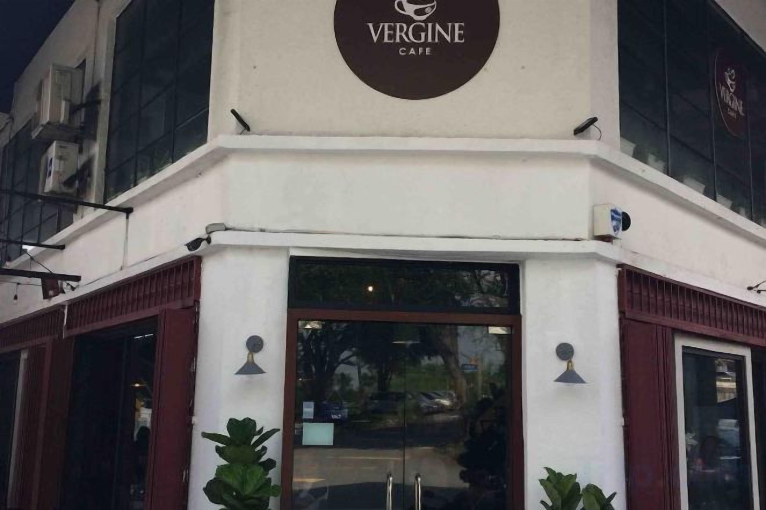 Exterior do Vergine Cafe, com uma placa chamativa acima da entrada.