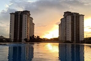 A swimming pool with two high-rise buildings in the background. - Beautiful Suria Kipark Damansara 3R2B Apartment (Batu)