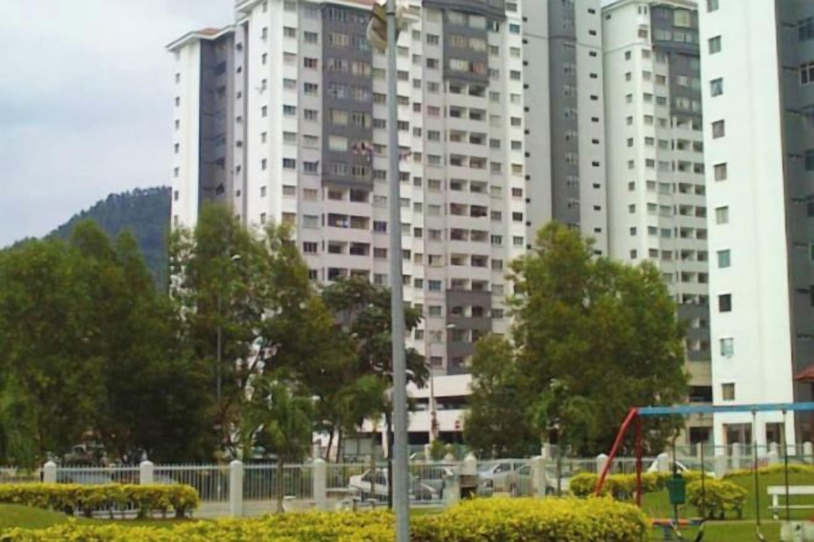 A multi-story residential building with balconies, surrounded by greenery and a playground.