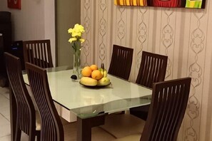 A dining table with chairs, a vase with flowers, and a fruit bowl. - Beautiful Suria Kipark Damansara 3R2B Apartment (Batu)