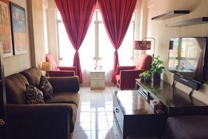 A living room with a sofa, chairs, a TV, and a small table. - Beautiful Suria Kipark Damansara 3R2B Apartment (Batu)