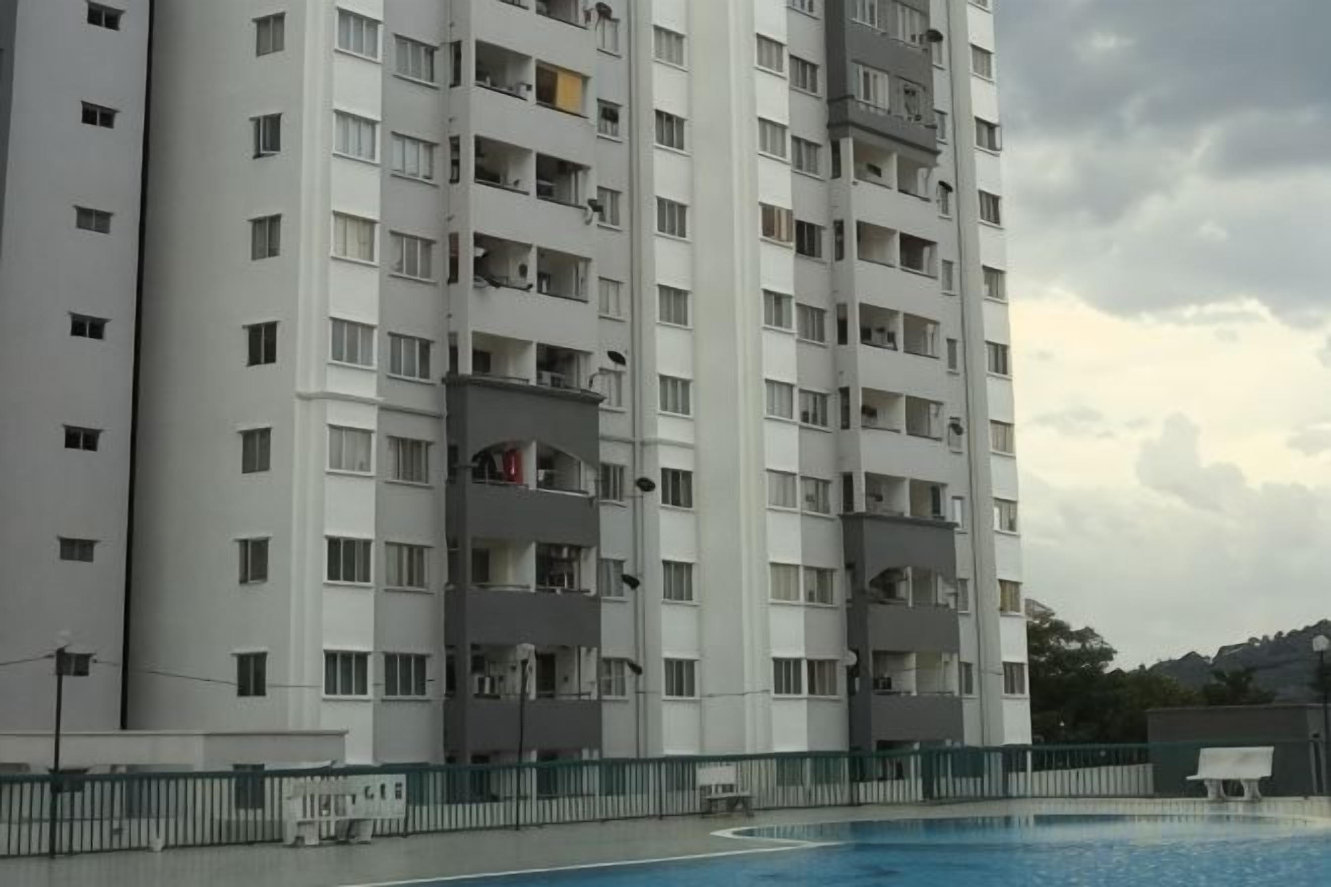 Um edifício residencial com vários andares, varandas, piscina e área cercada.