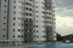 Un edificio residencial de varios pisos con balcones, piscina y zona vallada.