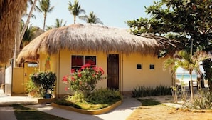 A thatched-roof building with a yellow facade, surrounded by tropical vegetation and palm trees. - Sunrise Beach Resort (Santa Fe)