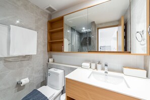 Een moderne badkamer met een grote spiegel, een wit wastafelmeubel en een toilet.