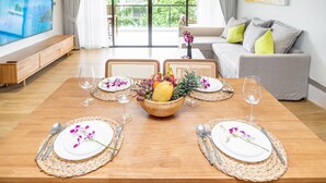Una mesa de comedor dispuesta con platos, cubiertos y una cesta de frutas.