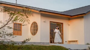 Una casa moderna con techo de tejas, puerta de madera y un pequeño banco de madera.
