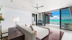 A modern hotel room with a bed, a desk, a television, and a balcony with a view of the ocean. - Ocean's 11 Villa (Phuket)