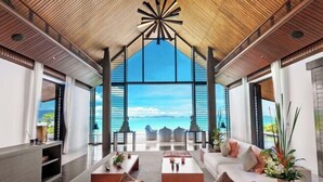 A spacious living area with a large window offering a view of the sea and mountains. - Ocean's 11 Villa (Phuket)