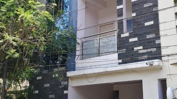 Um edifício residencial de vários andares com design moderno, apresentando fachada de vidro nos andares superiores e uma combinação de pedra e concreto nos níveis inferiores.