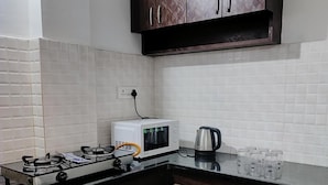 Uma cozinha com armários de madeira escura, fogão a gás, micro-ondas e chaleira no balcão.